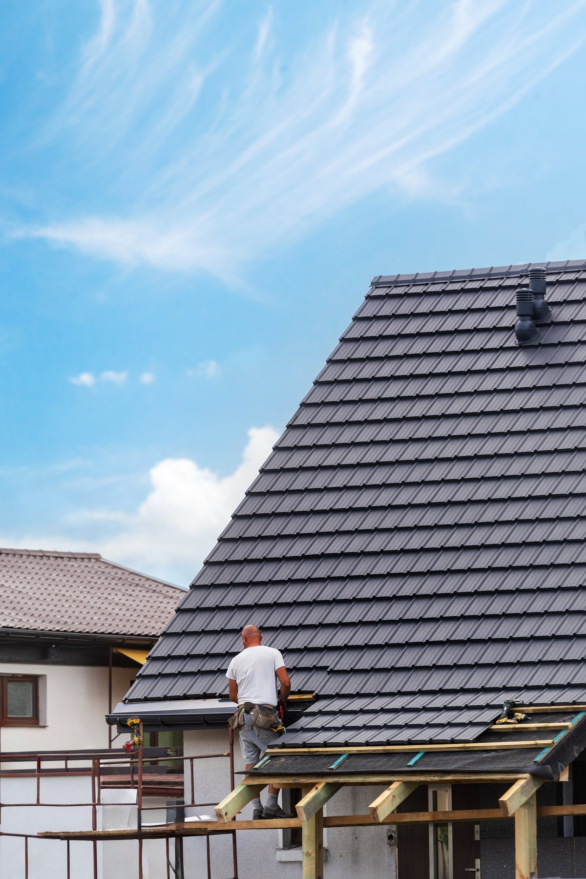 Roofer installing tiles on a sloped residential roof