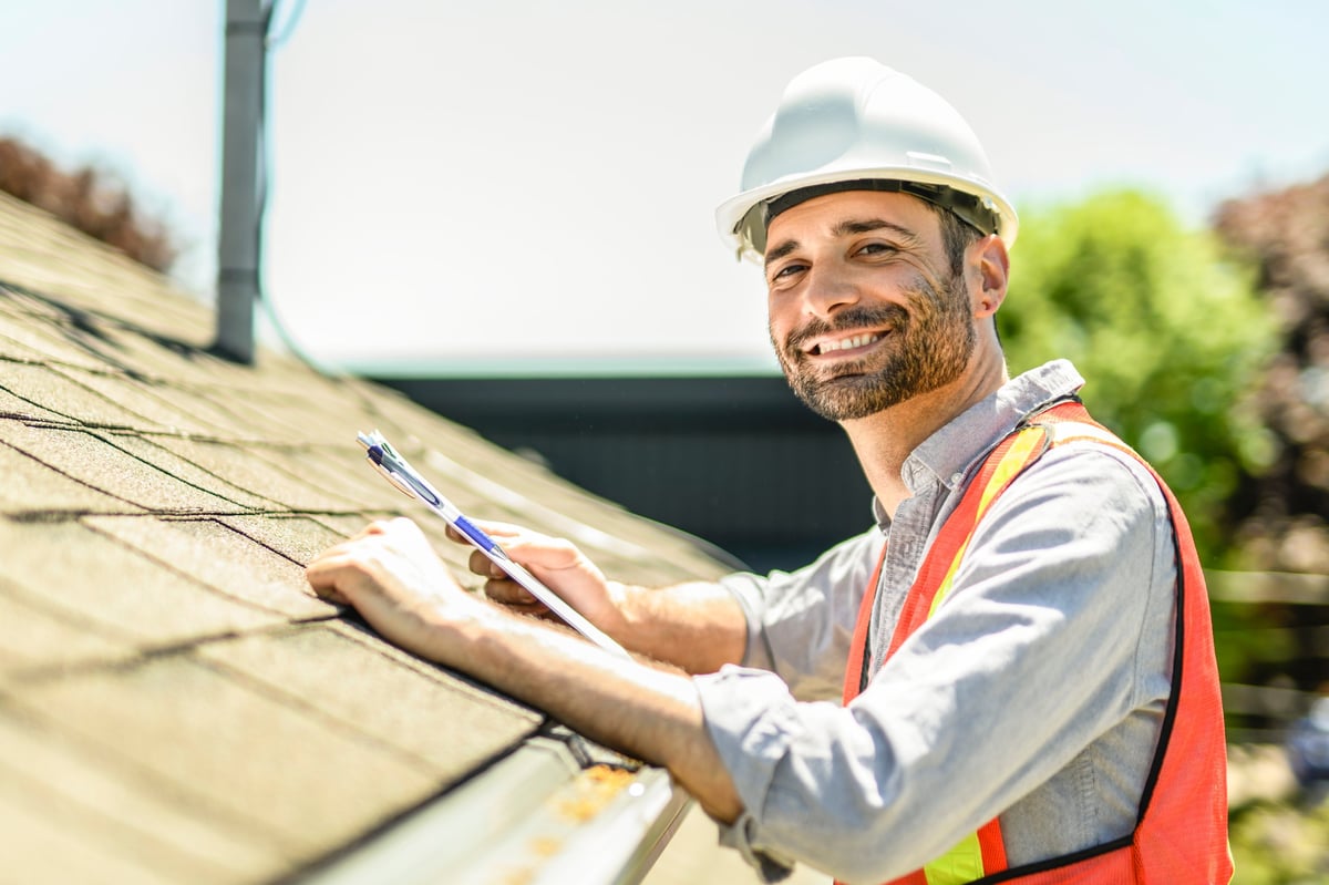 Inspector with clipboard reviewing a roof